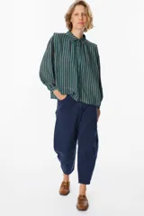 Camisa de manga larga con diseño de rayas verticales en tonos verde, azul y marrón. Presenta cuello clásico, cierre frontal con botones y mangas abullonadas con puños ajustados.