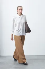 Camisa negra de estilo sastrero con cuello clásico, frente abotonado y mangas largas con puños ajustados. Presenta un diseño con hombreras sutiles que aportan estructura a la prenda.