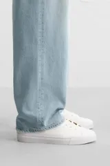 Zapatilla de cordones de caña baja, color negro, con capellada lisa y suela de goma blanca.