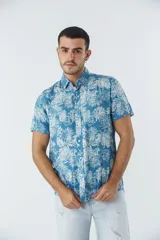 Camisa de manga corta con estampado botánico de hojas en tonos azul y blanco. Presenta cuello clásico, cierre frontal abotonado y corte slim.