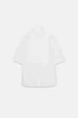 Camisa de algodón con cuello solapa y mangas por debajo del codo. Presenta un diseño con pechera plisada frontal, bajo recto y cierre mediante botones ocultos bajo solapa.