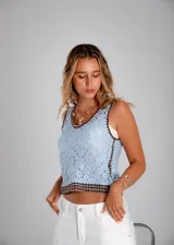 Blusa de crochet color beige con diseño calado, escote en V y terminaciones en color negro en el cuello, sisas y ruedo.