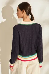Buzo de punto azul marino con cuello polo blanco y detalles de rayas de colores en el cuello, los puños y el ruedo. Cuenta con cierre frontal parcial de botones y diseño tejido de ochos.