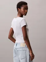 Remera de corte slim confeccionada en punto de algodón elástico con textura de canalé fino. Presenta cuello en V, manga corta y una insignia con el logo de Calvin Klein en el pecho.