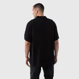 Camisa de manga corta en color gris oscuro, confeccionada en viscosa con cuello tipo cubano y cierre frontal de botones. Presenta un pequeño estampado circular en el pecho con la inscripción Black.