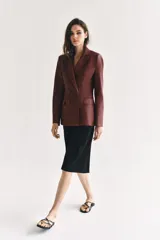 Blazer de cuero sintético en color beige, con cuello solapa, manga larga y bolsillos con solapa en el frente. Cierre frontal cruzado con botones a tono.