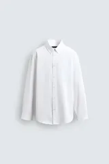 Camisa de corte regular fit confeccionada en tejido de algodón con textura. Presenta cuello abotonado, manga larga con puños abotonados y cierre frontal con botones.