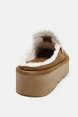 Mocasín destalonado de plataforma con acabado en gamuza color tostado. Presenta forro interior de efecto borreguito, detalle de antifaz en el empeine y pespuntes decorativos en contraste.