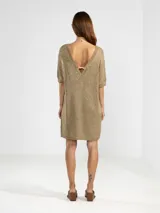Vestido corto de punto con hilos metálicos que aportan un brillo sutil. Presenta un calce relajado, cuello redondo, mangas cortas y espalda en V pronunciada con detalle de dije metálico.