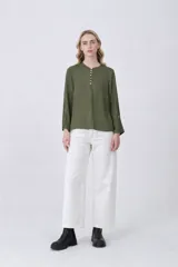 Blusa de poliéster color verde oliva, con cuello redondo y cierre frontal parcial de botones. Presenta mangas 3/4 con detalle de botón en el puño y un corte entallado.