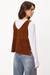 Chaleco de cuero gamuzado color marrón, con escote en V y cierre frontal mediante tiras para anudar.