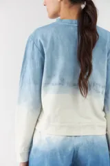 Buzo de cuello redondo y mangas largas, con diseño degradado en tonos celeste y blanco.