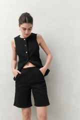 Bermuda negra de tiro medio con silueta recta y largo a la altura de la rodilla. Presenta bolsillos laterales y traseros, y costuras visibles.