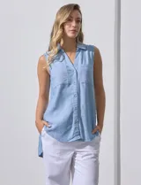 Camisa sin mangas color celeste, confeccionada en lino. Presenta cuello camisero, escote en V, abertura frontal con botones, dos bolsillos de parche en el pecho y terminación con botones en los laterales.