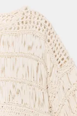 Top cropped de punto con diseño combinado de texturas, cuello redondo y mangas cortas amplias. Presenta una estructura calada con detalles de cintas verticales.