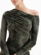 Top de lycra estampado con diseño de estrellas, con escote irregular, drapeado en el pecho y mangas largas. Presenta un calce ajustado al cuerpo.