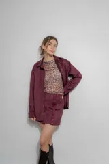 Falda corta de gamuza color bordó, con detalle de bordado geométrico vertical en el frente y bolsillo decorativo lateral.