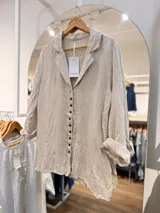 Camisa Ciara de lino color beige, con cuello camisero abierto, manga larga y botonera frontal de botones oscuros.