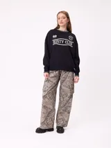 Pantalon cargo de corte recto y tiro medio, con estampado de camuflaje tipo bosque en tonos beige y marrones. Cuenta con bolsillos laterales tipo cargo con solapa y cierre de botón.