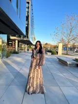 Vestido largo de animal print con cuello redondo, mangas largas abullonadas y falda escalonada.