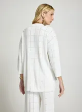 Camisa de punto calado color blanco, con cuello polo y cierre frontal de botones. Diseño de manga corta y patrón de cuadros sutiles.