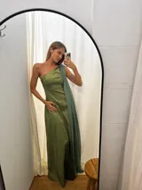 Vestido largo de fiesta color verde, confeccionado en tafeta con brillo y gasa. Presenta un diseño de un solo hombro con una capa de seda liviana integrada que permite diversas formas de uso, aportando movimiento y elegancia.