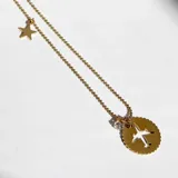 Collar dorado de cadena fina con dije redondo calado con forma de avión y dije de estrella.