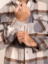 Camisa de franela a cuadros en tonos beige, gris y marrón, con corte regular fit, cuello clásico, cierre de botones frontales y dos bolsillos con solapa en el pecho.
