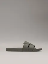 Ojotas tipo slide de color verde oliva, con doble tira superior de TPU con relieve y logotipo grabado. Cuentan con plantilla moldeada ergonómica con soporte para el arco plantar y suela de EVA.