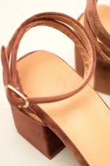 Sandalia de tacón cuadrado medio, confeccionada en terciopelo negro. Presenta un diseño de tiras cruzadas con nudo en la parte delantera y una tira ajustable con hebilla en el tobillo.