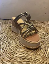 Sandalias con plataforma de cuero color dorado, con tiras gruesas con nudos y taco de madera y goma de 7cm de altura. Hechas a mano en Uruguay.