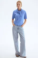 Remera de punto suave de algodón, color celeste, con hombros caídos, mangas cortas y detalle de cuello tipo fular con lazo integrado.