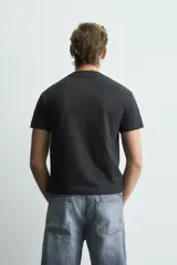 Remera negra de corte cropped, con cuello redondo y manga corta. Presenta estampado frontal con texto en efecto desgastado.