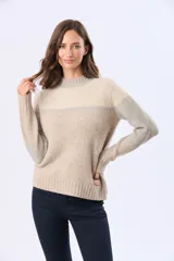 Buzo tejido de punto con diseño de bloques de color en tonos rosa, beige y gris. Presenta cuello redondo, mangas largas y corte holgado.