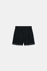 Shorts de satén negro con cintura elástica en la espalda, bolsillos delanteros y detalles de puntilla a tono en el ruedo.