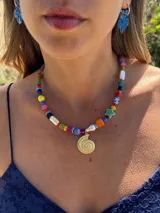 Collar corto con cuentas de colores y dije dorado en forma de caracol.