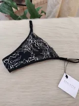 Microtanga de encaje con diseño floral bitono en negro y blanco, con laterales finos ajustables.