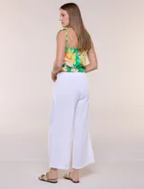 Top crop de rayón con estampado floral tropical en tonos verdes, amarillos y blancos. Presenta escote recto, frunces elastizados en el pecho y la cintura, y tirantes finos para anudar en los hombros.