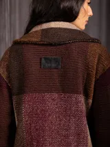 Chaquetón largo de paño con diseño de cuadros en tonos tierra, borravino y negro. Presenta cuello solapa, bolsillos laterales y forro interior.