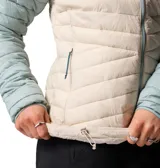 Campera técnica Columbia modelo Powder Pass con tecnología Omni-Shield resistente al agua y aislamiento térmico Thermarator. Presenta un diseño de bloques de color en tonos celeste y beige, con cierre frontal completo, cuello alto con protección para la barbilla y bolsillos laterales con cremallera.