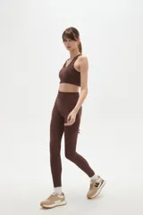 Calza deportiva de tiro alto y ajuste ceñido al cuerpo, confeccionada en tejido elástico de color bordó.
