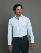 Camisa de vestir de manga larga en color celeste, con cuello clásico, cierre frontal de botones y bolsillo en el pecho.