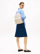 Mochila color crema de poliuretano con cierre de cremallera, asa superior, correas ajustables con inscripción de la marca y bolsillo exterior con cremallera.