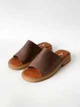 Sandalias de cuero color chocolate, con faja ancha en el empeine, plantilla de gamuza y suela plana con taco bajo.