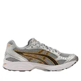 Championes Asics Gel-Kayano 14, de color gris con detalles metalizados plateados y franjas laterales negras con bordes naranjas.