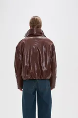 Campera de eco-cuero color marrón con cuello alto, cierre frontal oculto y bolsillos laterales. Presenta un diseño acolchado con acabado brillante.