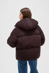 Campera puffer de color marrón oscuro, con diseño capitoneado, cierre frontal, capucha ajustable y bolsillos laterales con cierre.