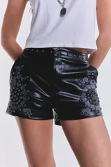 Short negro de cuero sintético, tiro bajo, con tachas y bordado floral en el lateral.