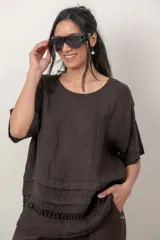 Blusa de lino color blanco, de corte amplio, con escote redondo, mangas cortas y detalle de guarda calada horizontal en la parte inferior.