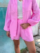 Conjunto de dos piezas confeccionado en lino color blanco. Incluye una camisa de corte holgado con mangas abullonadas y bolsillos frontales, y un short de tiro alto con cintura elástica y forro interior.